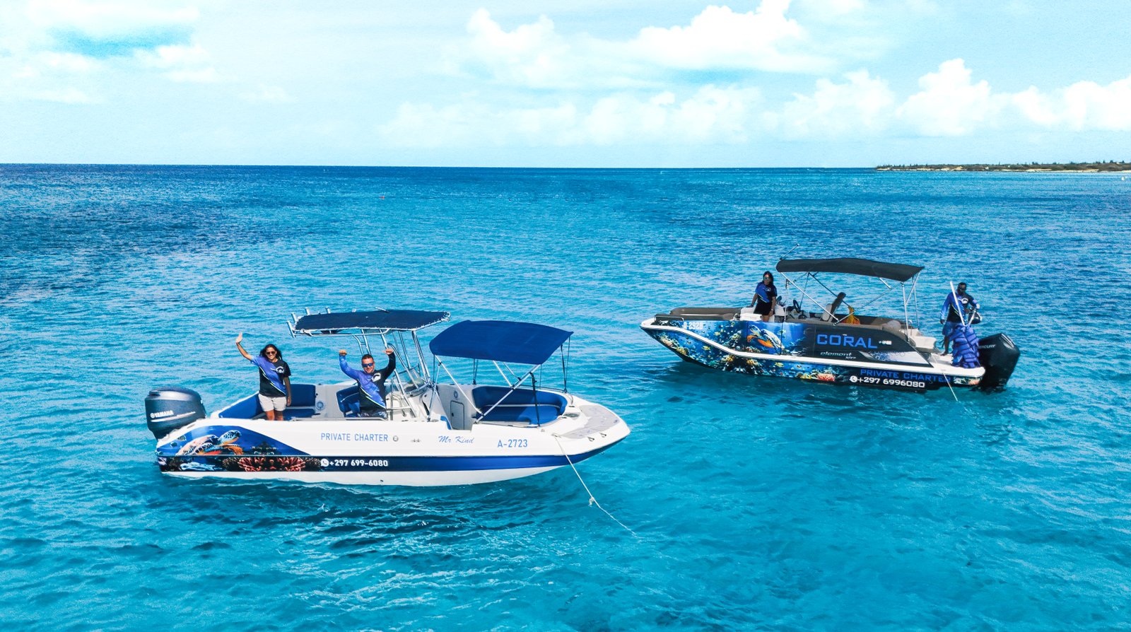 Two private tour boats anchored at a turquoise snorkeling spot in Aruba